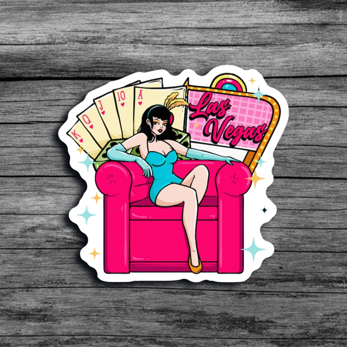 A sticker of a woman wearing bunny ears, a short blue dress, and light blue gloves, sitting on a big pink chair with a Las Vegas sign and cards representing a straight flush in poker
