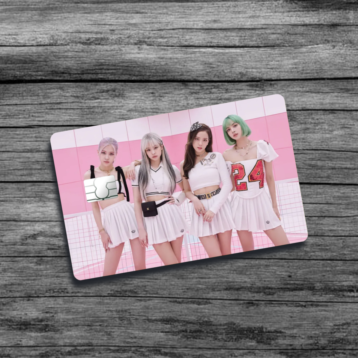 A credit card skin featuring K-pop group Black Pink with 4 women wearing skirts and sporty tops, in front of a multi-shaded pink background.