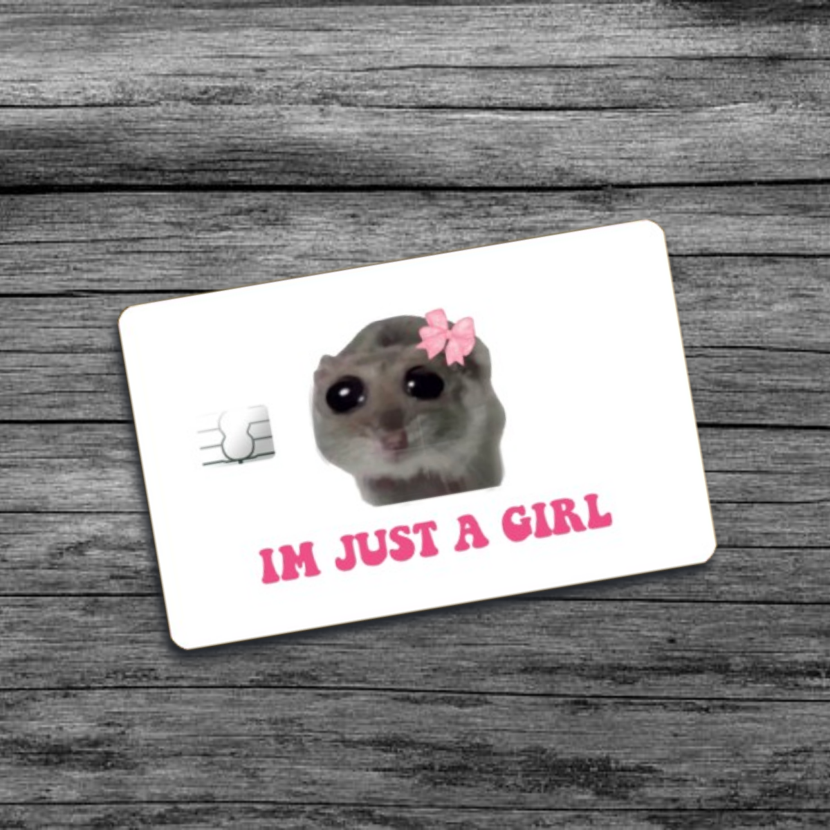 A credit card skin featuring the I'm Just A Girl meme: a hamster with a pink bow and wide beady eyes, set against a white background.
