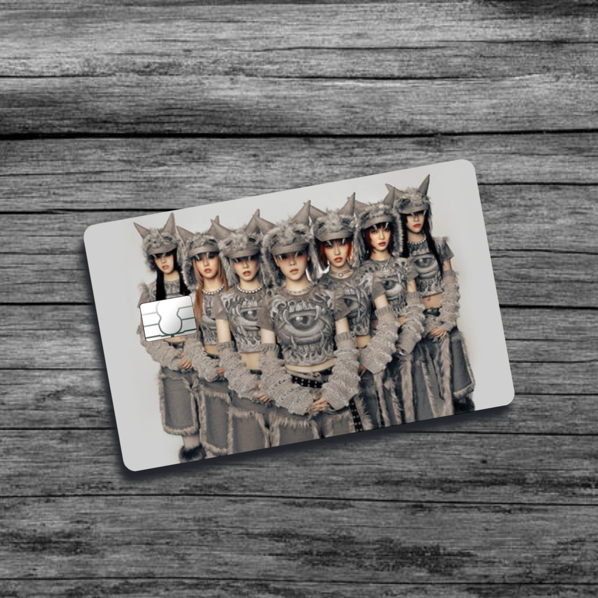 A credit card skin featuring K-Pop group XG, seven women with wolf-like, furry, tribal clothing and hats, standing in an offsetting triangular pattern.