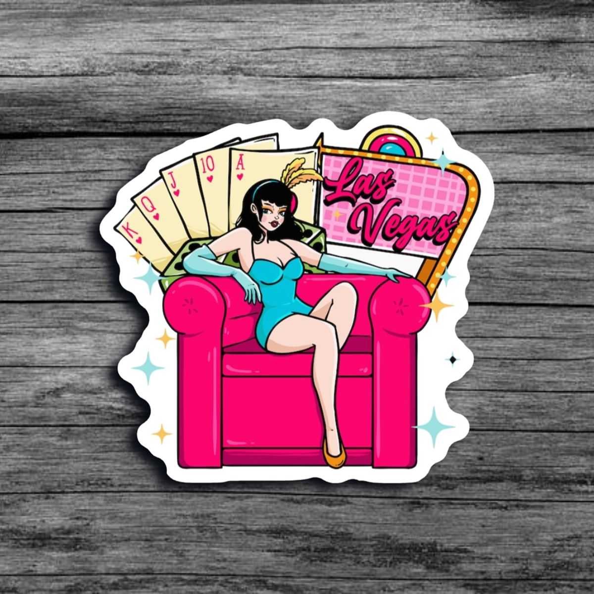 A sticker of a woman wearing bunny ears,  a short blue dress, and light blue gloves, sitting on a big pink chair with a Las Vegas sign and cards representing a straight flush in poker 