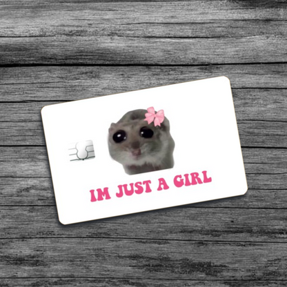 A credit card skin featuring the I'm Just A Girl meme: a hamster with a pink bow and wide beady eyes, set against a white background.