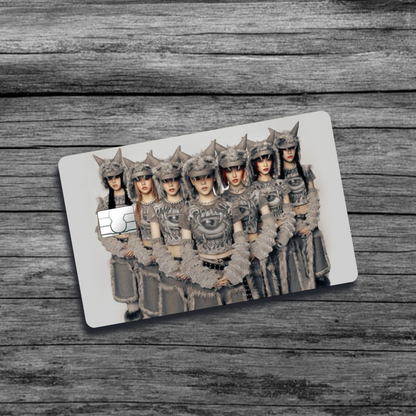 A credit card skin featuring K-Pop group XG, seven women with wolf-like, furry, tribal clothing and hats, standing in an offsetting triangular pattern.