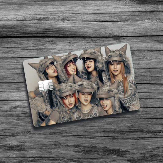 A credit card skin featuring K-Pop group XG, seven women with wolf-like, furry, tribal clothing and hats, with sharp teeth, making various mischievous facial expressions. 